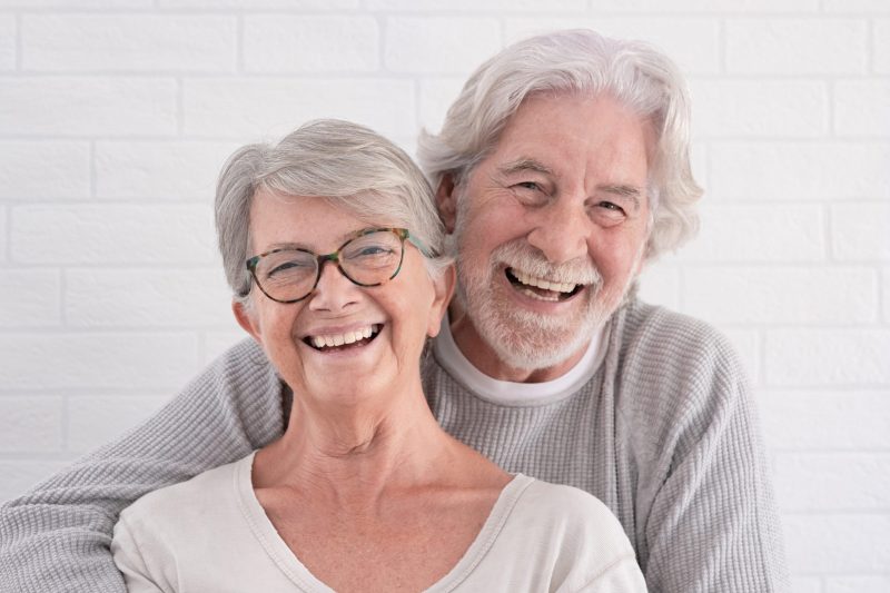 Cheerful couple of two beautiful senior people hugging each other standing having fun at home serene retirement concept